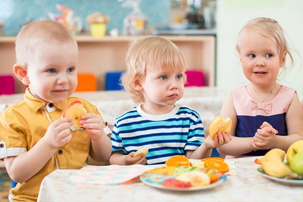 Happy young little preschoolers eating healthy foat a Preschool & Daycare Serving Hesperia, CAods