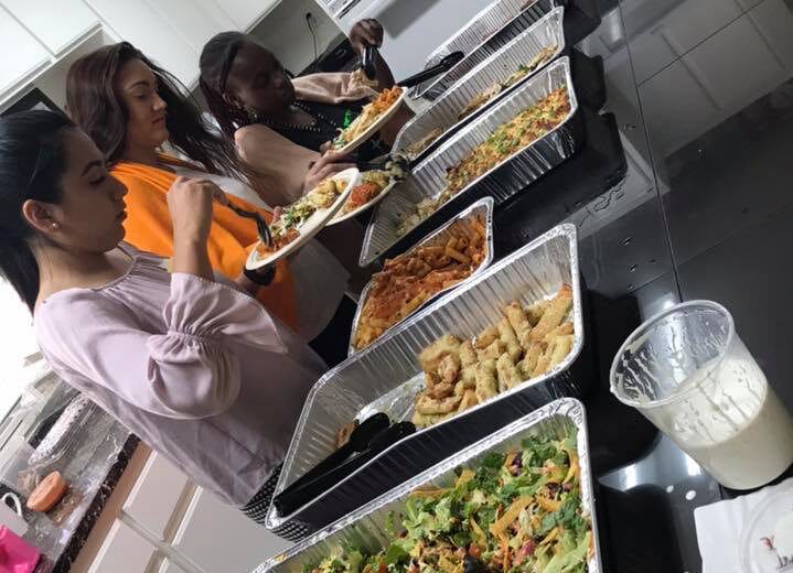 Group of parents eating together on a buffet , with salad, and pasta on a tray foil at a Preschool & Daycare Serving Hesperia, CA