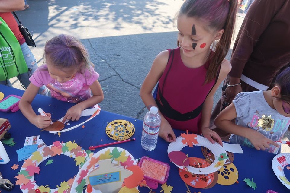 Preschoolers doing an art project cutting colorful flower shaped design on a cut paper plates at a Preschool & Daycare Serving Hesperia, CA