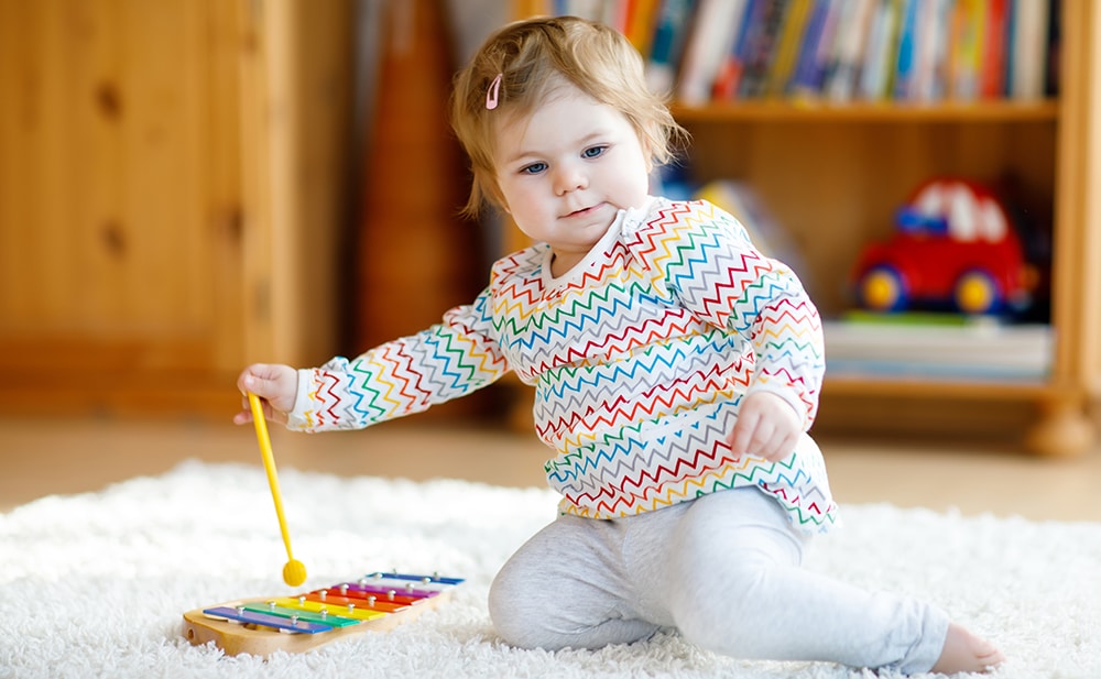 Adorable cute beautiful little baby girl playing with educational wooden music toys at home or nursery. Toddler with colorful xylophon. Happy healthy child having fun. Kid learning skills at a Preschool & Daycare Serving Hesperia, CA