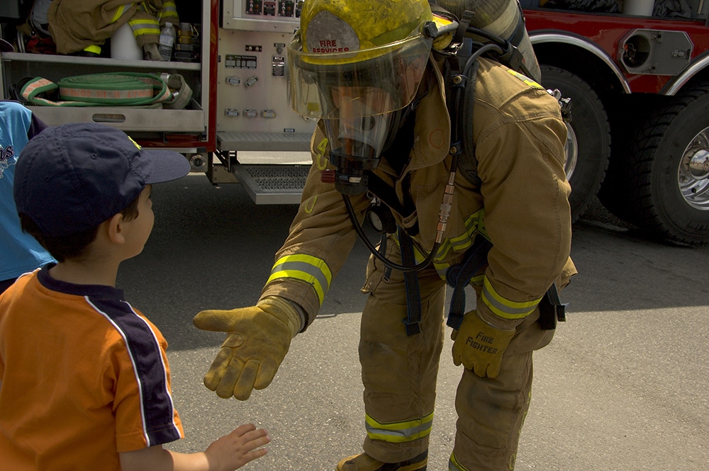 Firefighter in uniform greeting a child at a Preschool & Daycare Serving Hesperia, CA