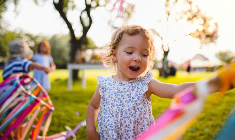 A front view of small toddler girl on birthday party outdoors in garden in summer at a Preschool & Daycare Serving Hesperia, CA