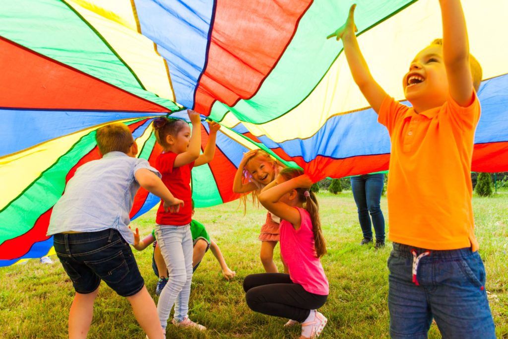 Group of preschoolers enjoying playing under a colorful tent cover at a Preschool & Daycare Serving Hesperia, CA
