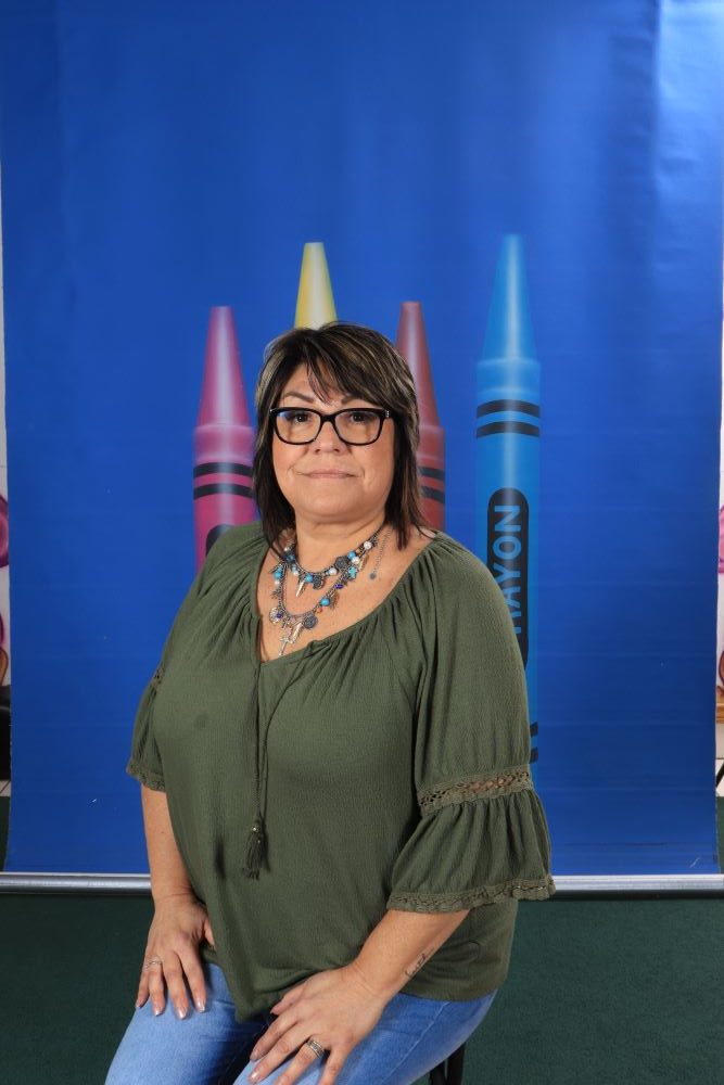 Ms_Linda happy preschool teacher with a crayon and blue background at a Preschool & Daycare Serving Hesperia, CA