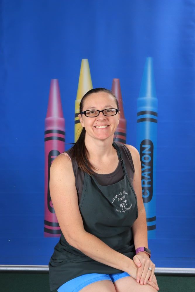 Ms_Rebecca happy preschool teacher with a crayon and blue background at a Preschool & Daycare Serving Hesperia, CA