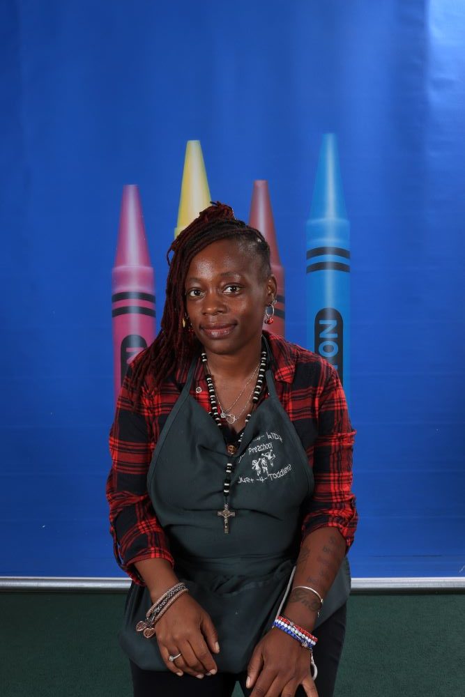 Ms_Tasha happy african american preschool teacher with a crayon and blue background at a Preschool & Daycare Serving Hesperia, CA