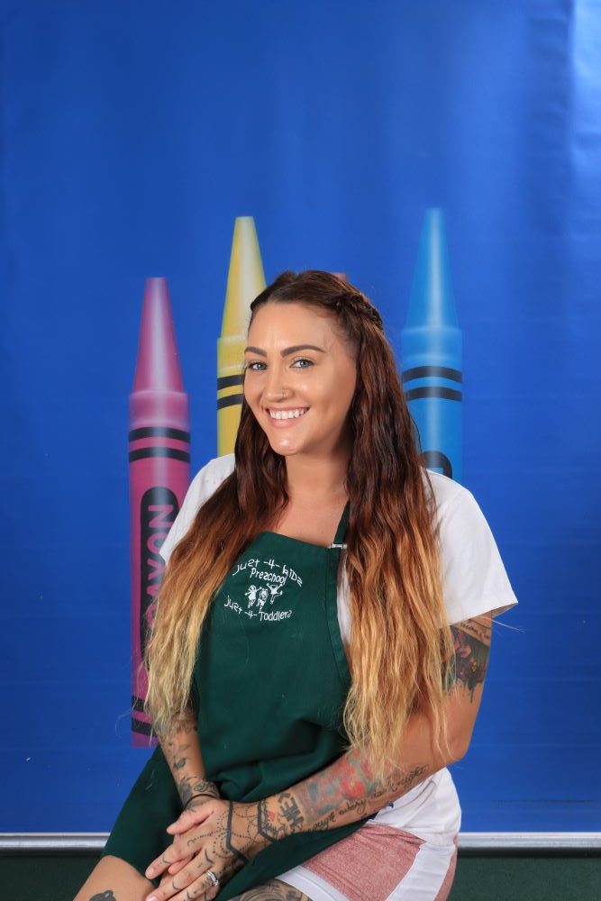Ms_Trina happy preschool teacher with a crayon and blue background at a Preschool & Daycare Serving Hesperia, CA